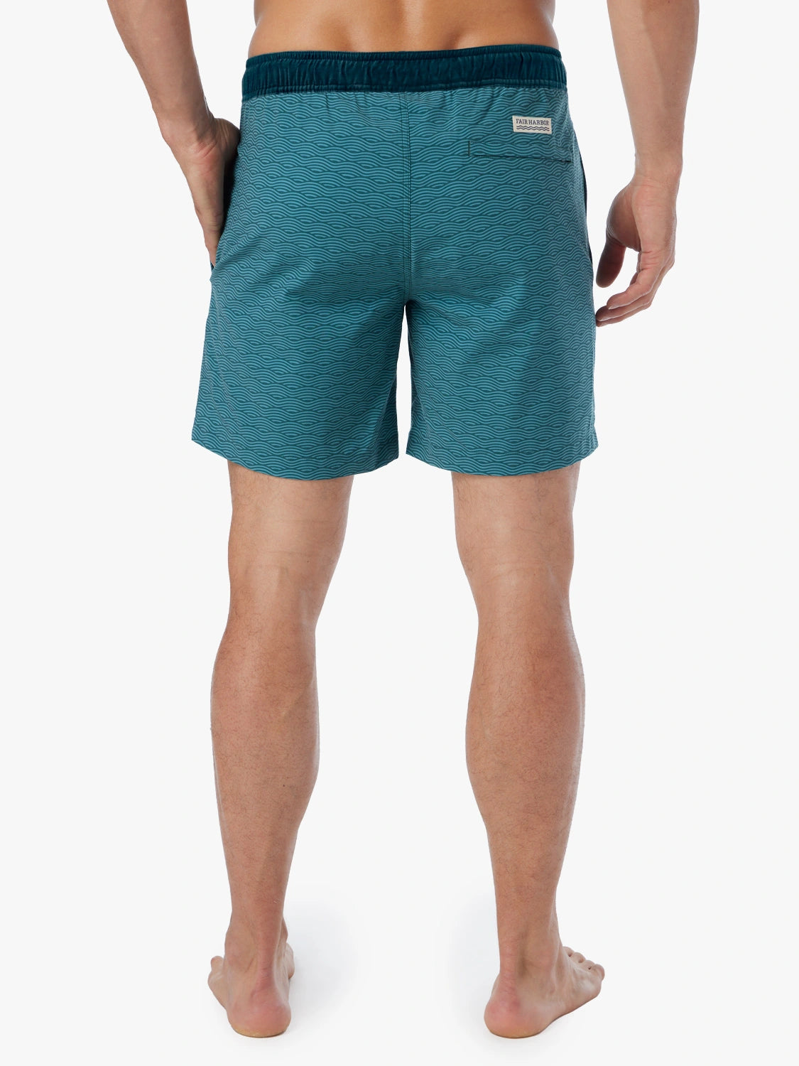 Person wearing a pair of green wave Bayberry swim trunks with a drawstring waistband, showing the back view. 