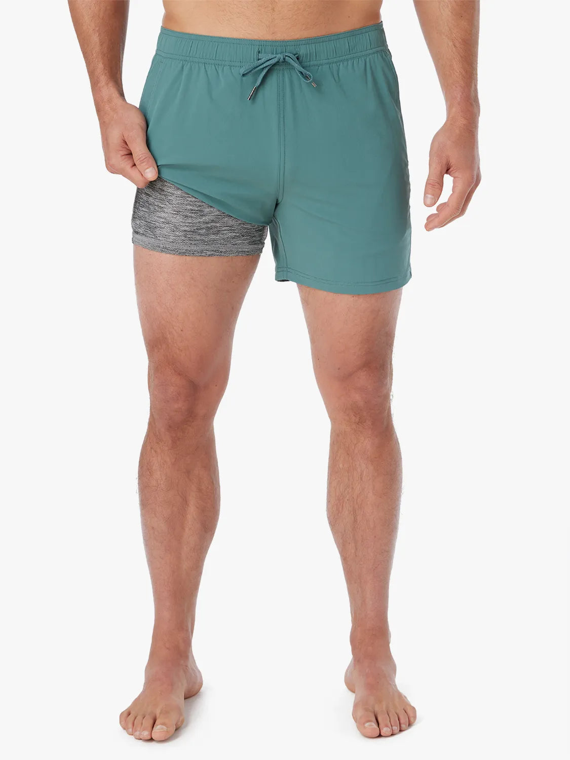 Person wearing solid seapine green bungalow trunk with drawstring on a white background. Showing the liner underneath.