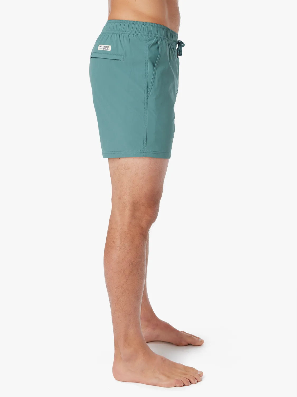 Person wearing solid seapine green bungalow trunk with drawstring on a white background. Showing the side view.