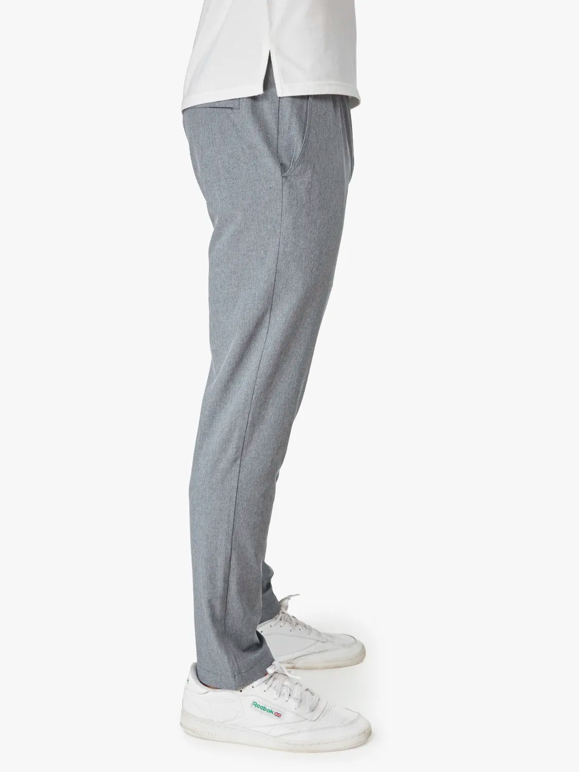Person wearing a pair of grey one pant with a drawstring on a white background. Pairing with white shirt and sneakers, showing the side view. 