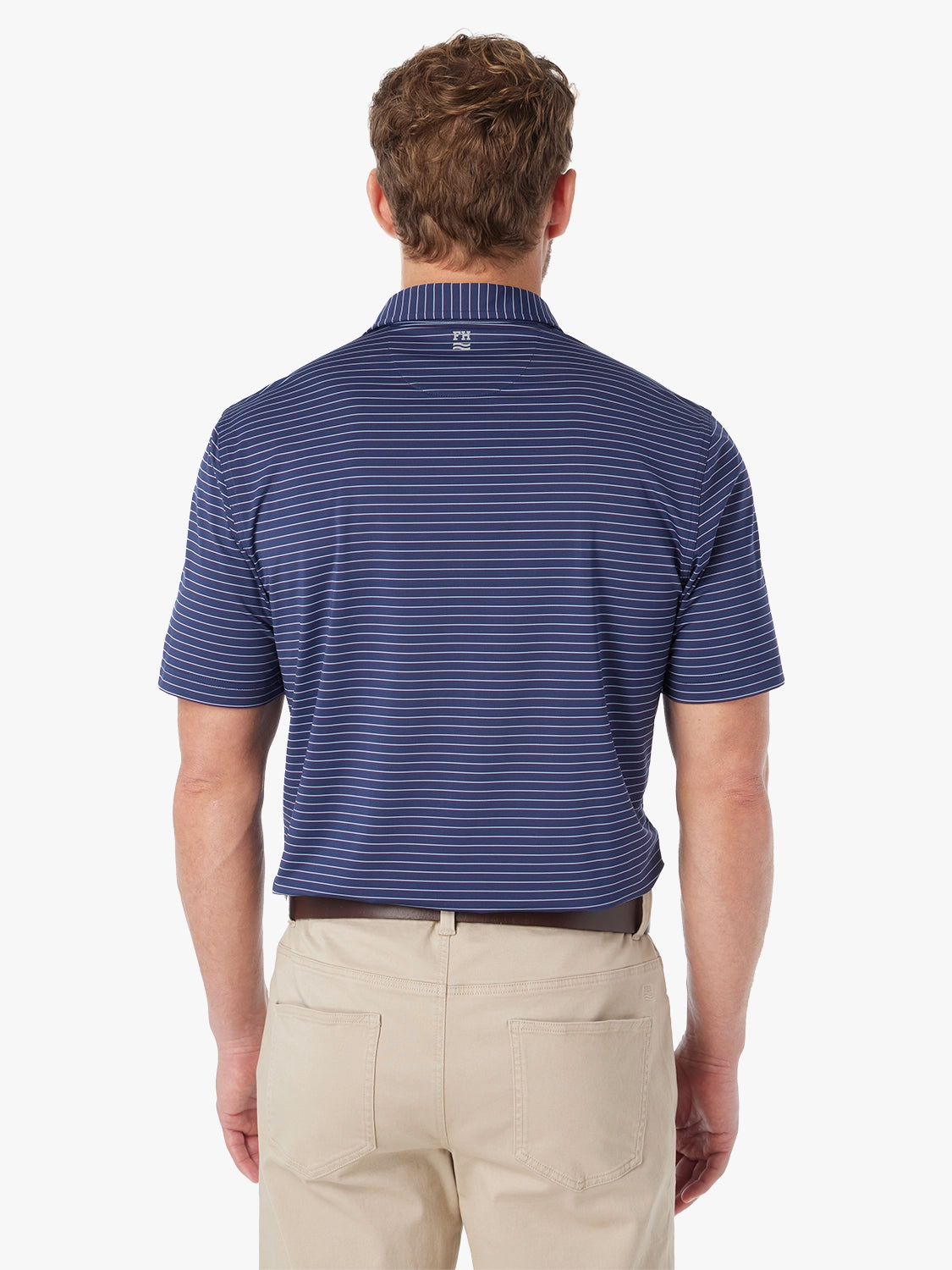 Man wearing navy blue striped compass polo shirt on a white background, paired with khaki pants. Showing the back view of polo 