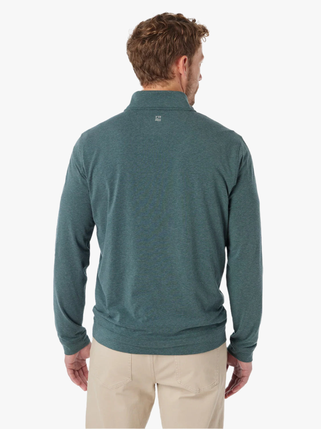 Man wearing olive green compass pullover with a quarter zip on a white background, paired with khaki pants. Showing the back view of quarter zip with visible logo at back of neck. 