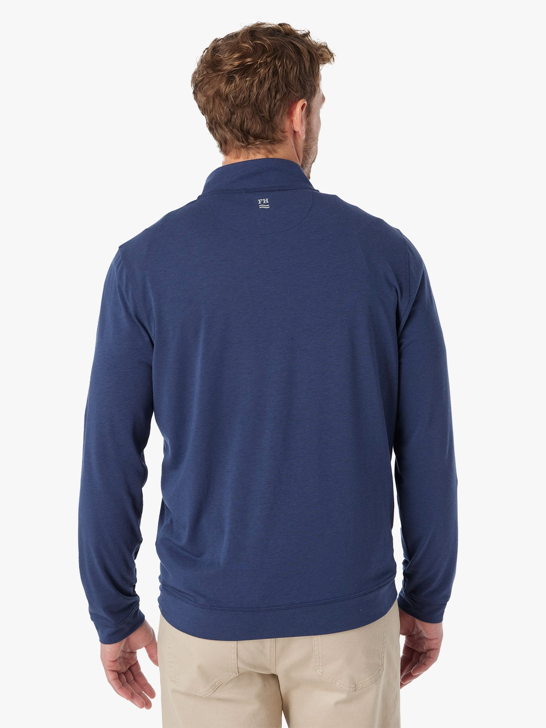 Man wearing a navy blue pullover with a visible brand logo on the back against a white background