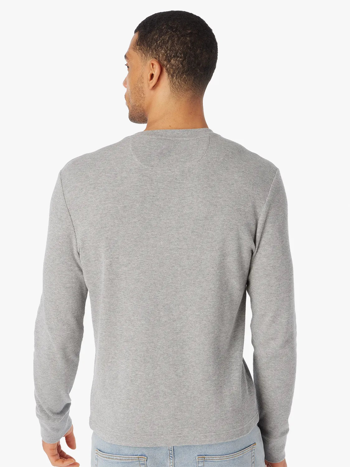 Man wearing a gray long-sleeve waffle henley shirt on a white background. Paired with jeans and showing the back view. 