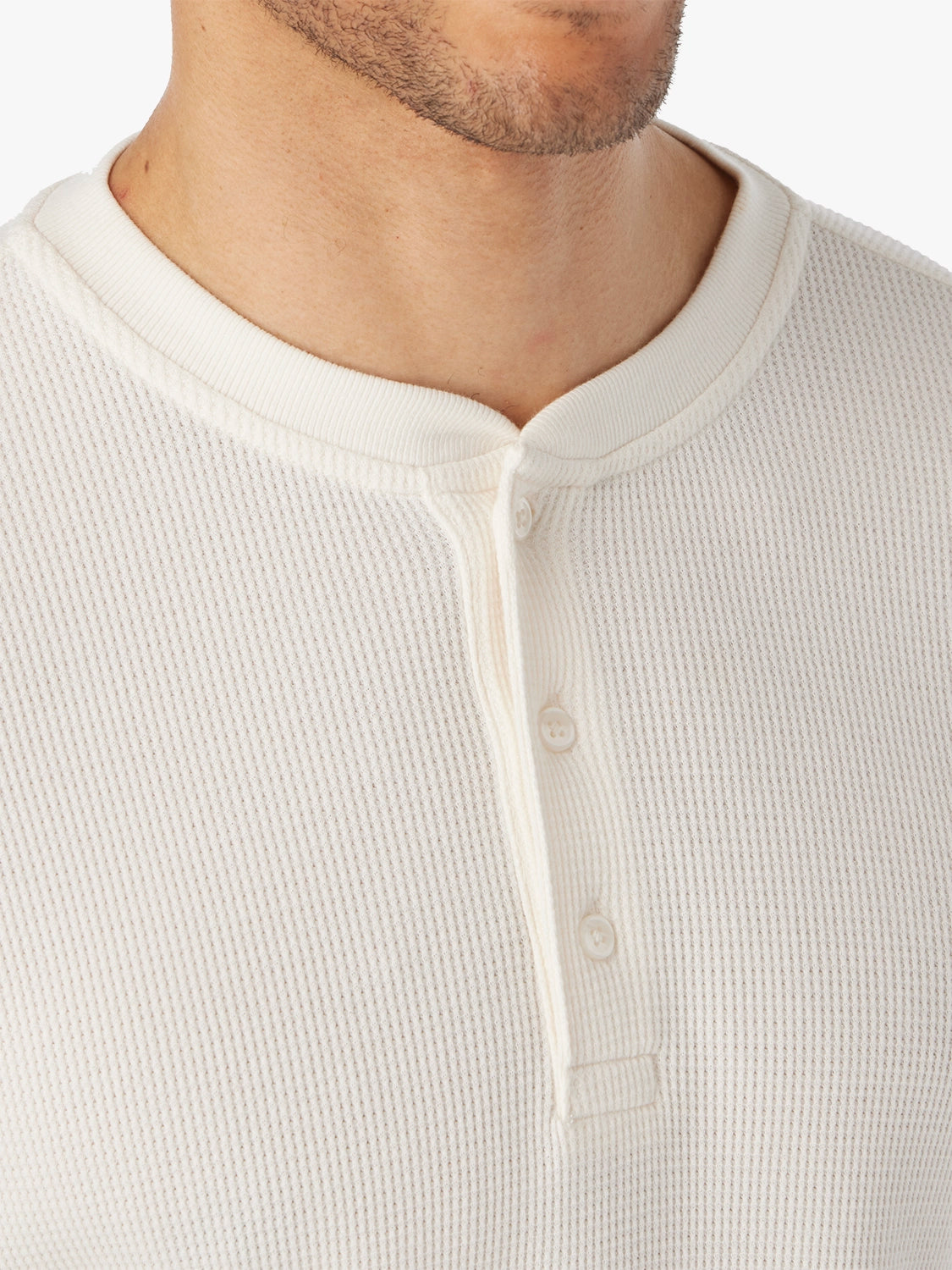 Close-up of a cream waffle fabric and  henley buttons of shirt worn by a person