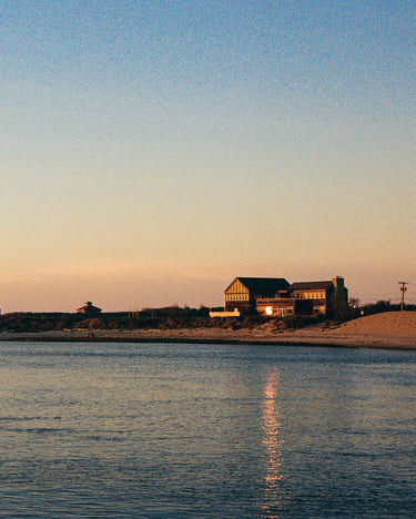 Coastal scene with buildings silhouetted against a sunset sky over water