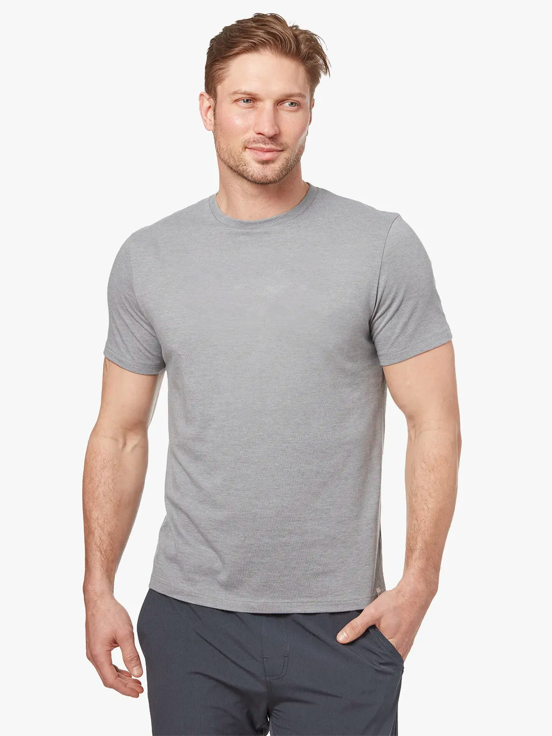 Person wearing grey kismet t-shirt on a white background, paired with black one pants. 