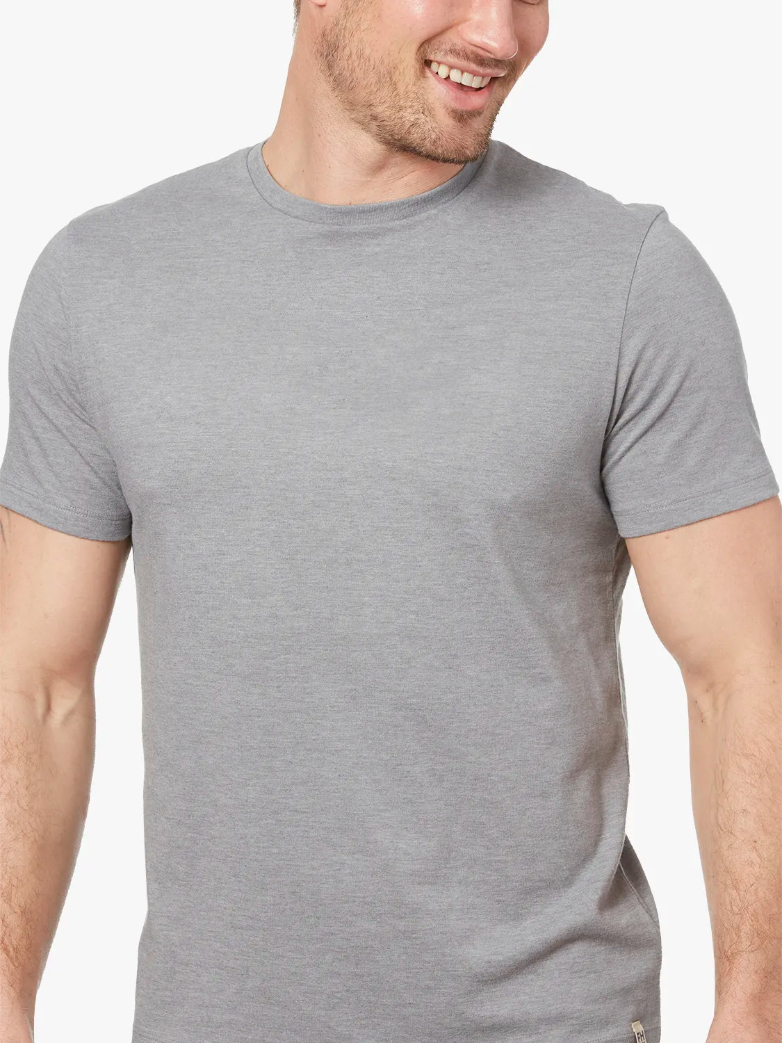 Close up of person wearing grey kismet t-shirt on a white background. 