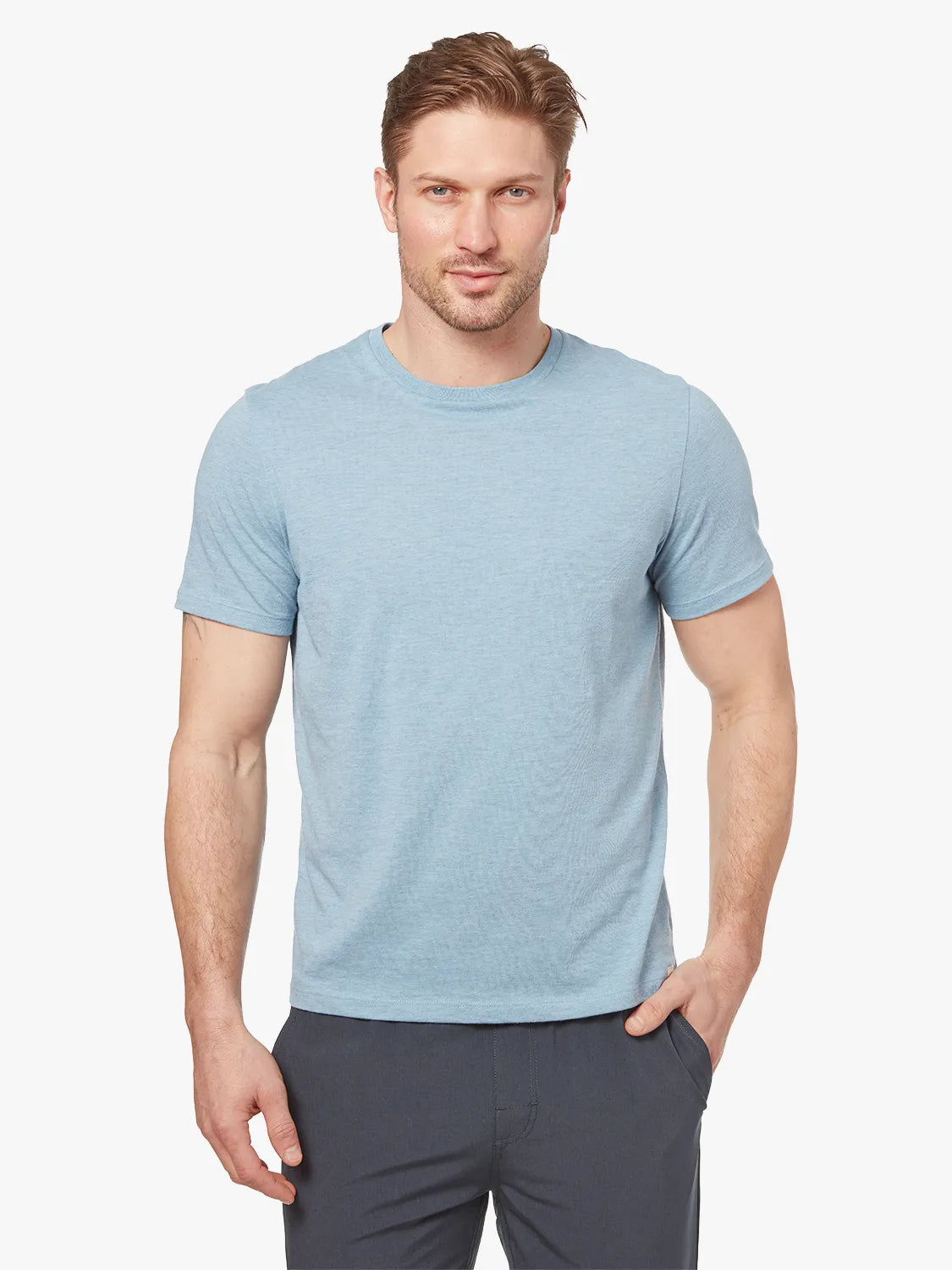 Person wearing light blue kismet t-shirt on a white background, paired with black one pants. 