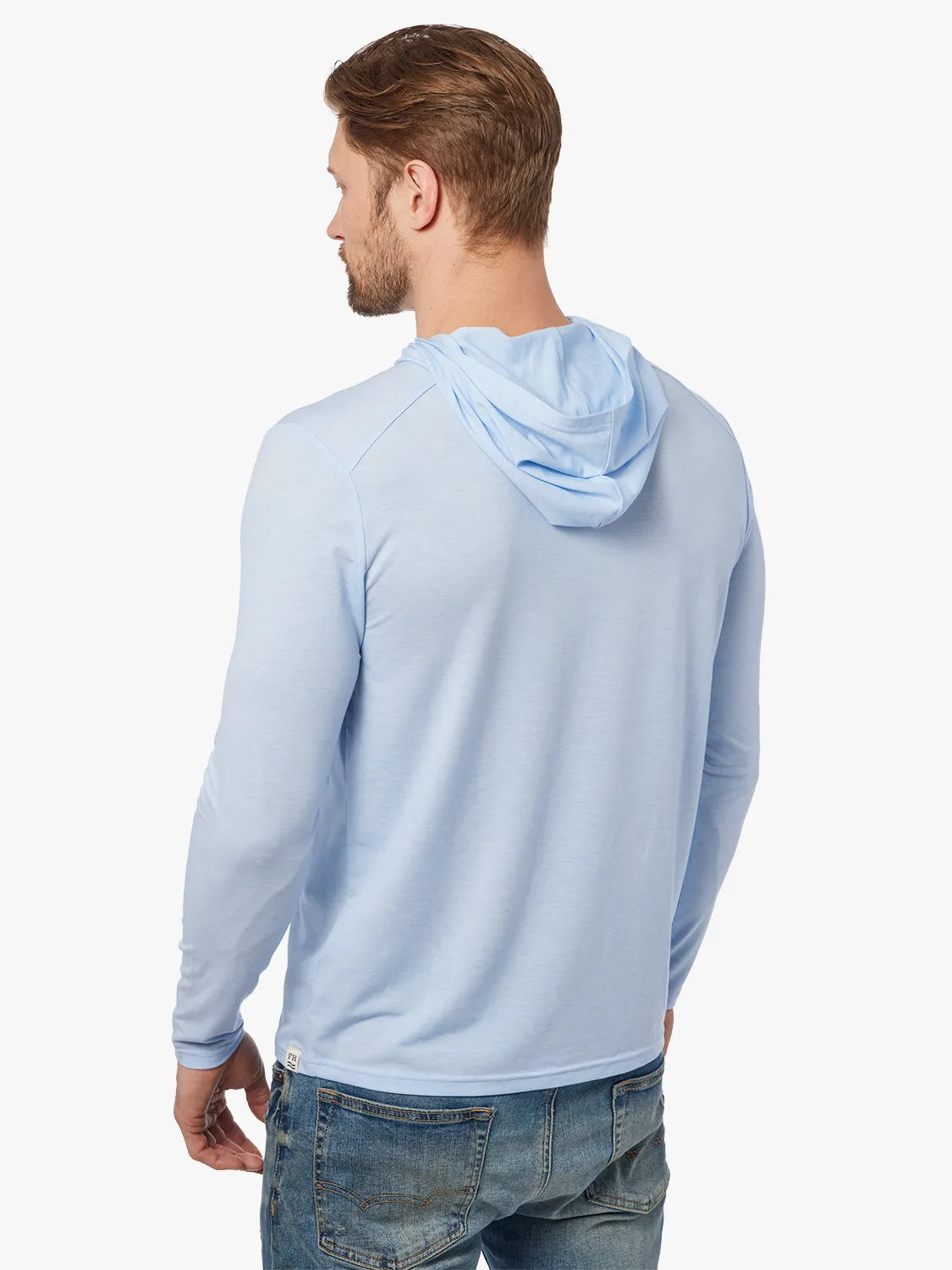 Person wearing light blue seabreeze hoodie on a white background, paired with denim pants. Showing the back view of hoodie. 