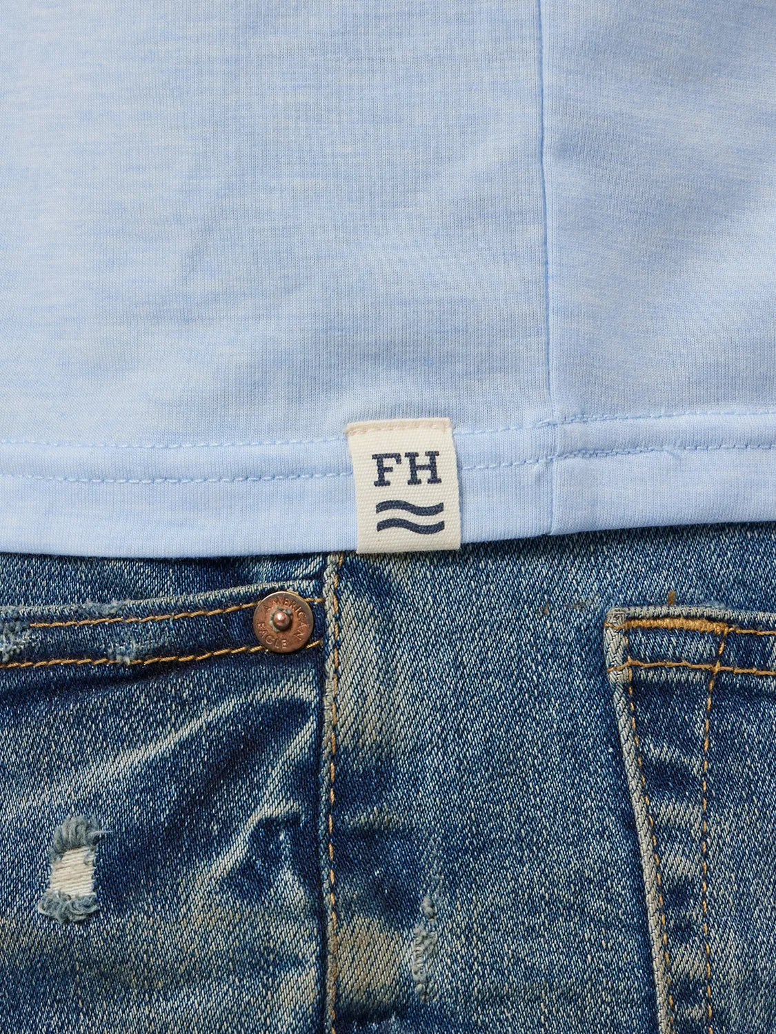 Close up of wearing navy blue seabreeze hoodie showing the fabric and brand logo patch.  