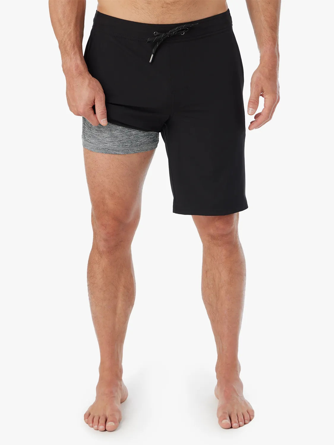 Person wearing a pair of black Ozone shorts with drawstring on a white background, showing the liner. 