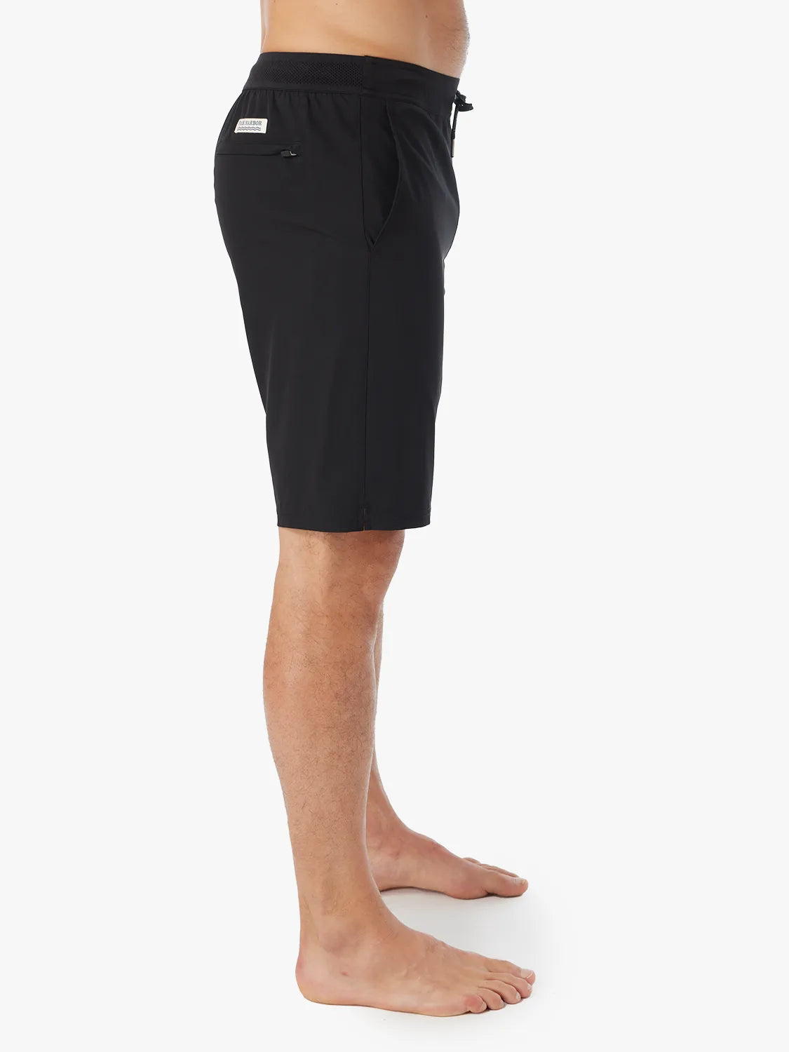 Person wearing a pair of black Ozone shorts with drawstring on a white background, showing the side view. 