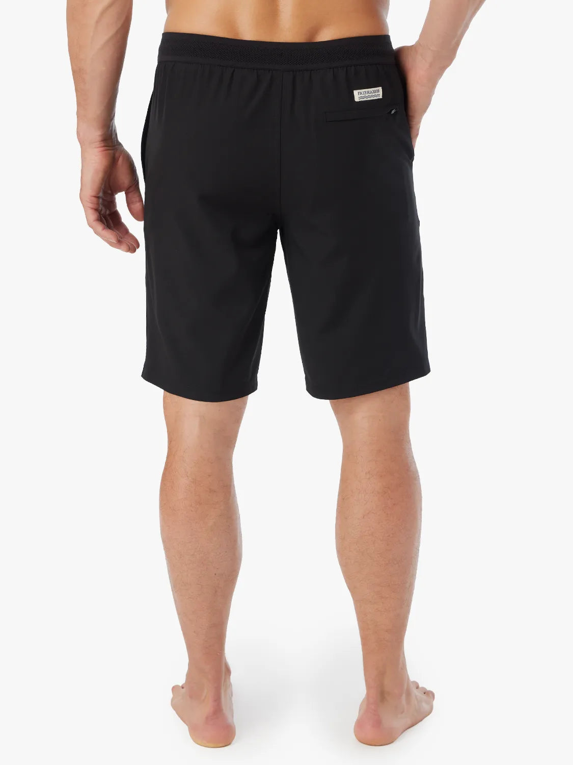 Person wearing a pair of black Ozone shorts with drawstring on a white background, showing the back view. 