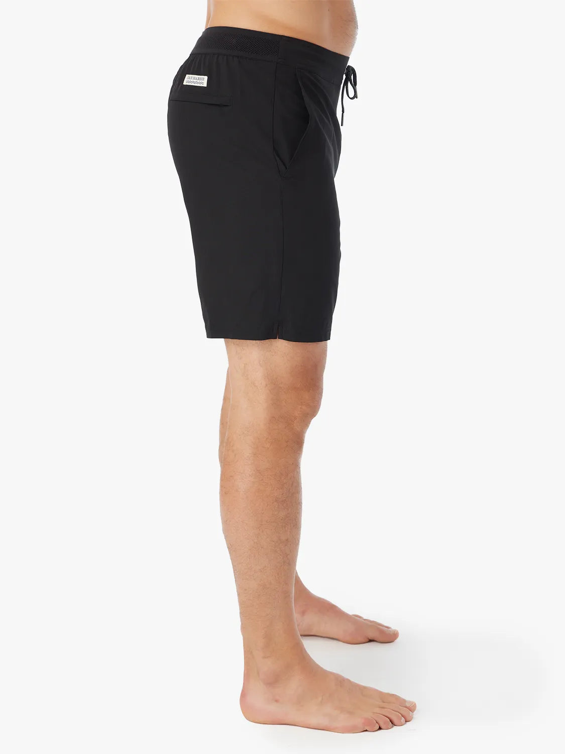 Person wearing a pair of black Ozone shorts with drawstring on a white background, showing the side view. 