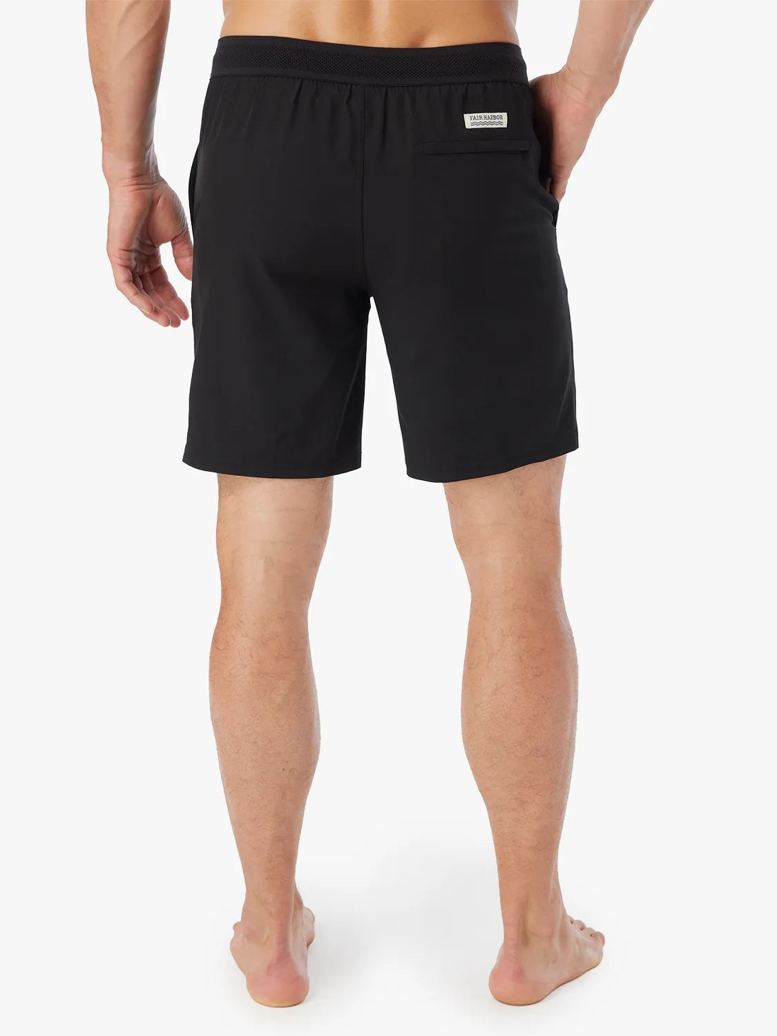 Person wearing a pair of black Ozone shorts with drawstring on a white background, showing the back view. 