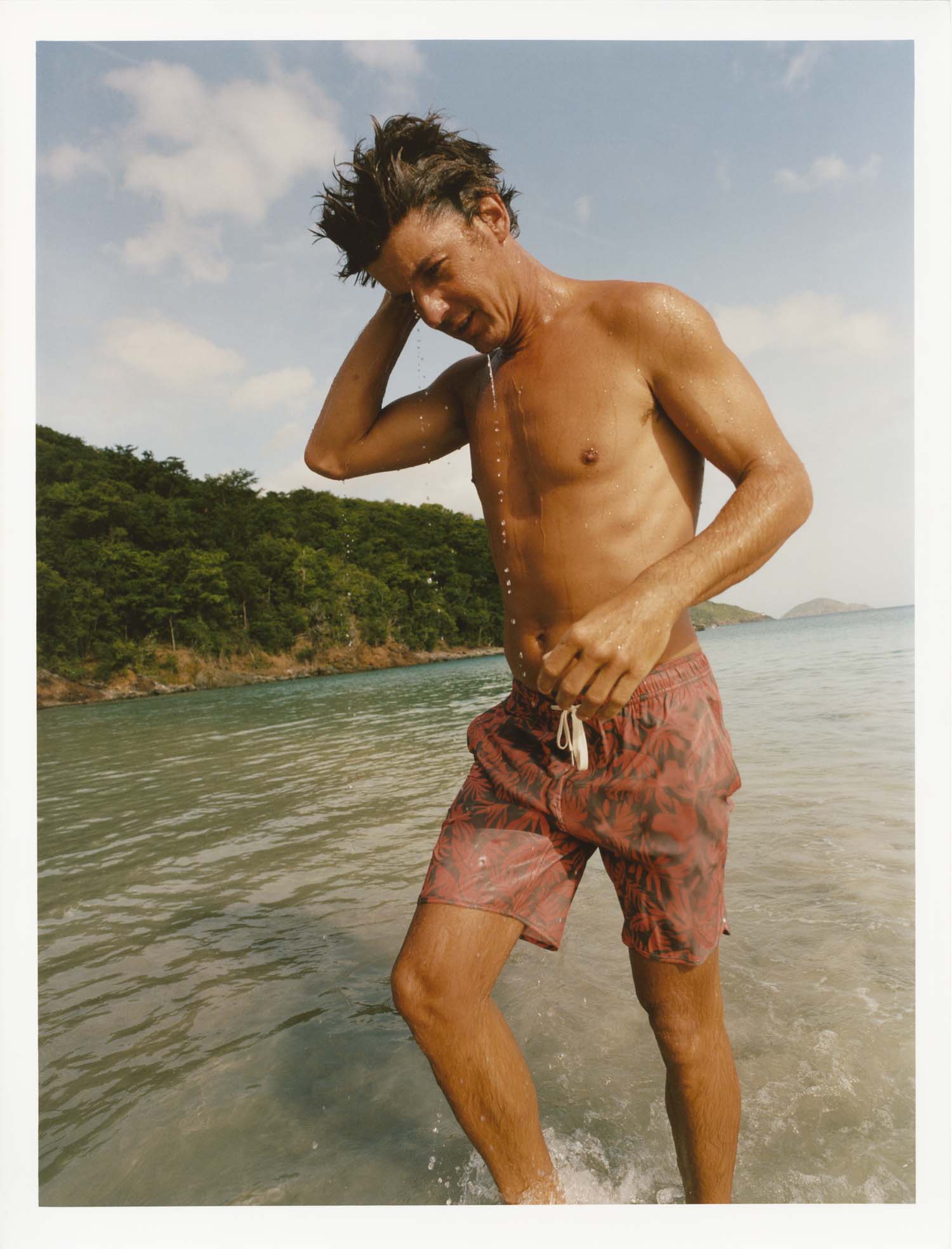 Man in Anchor Trunk standing in shallow water with a scenic background