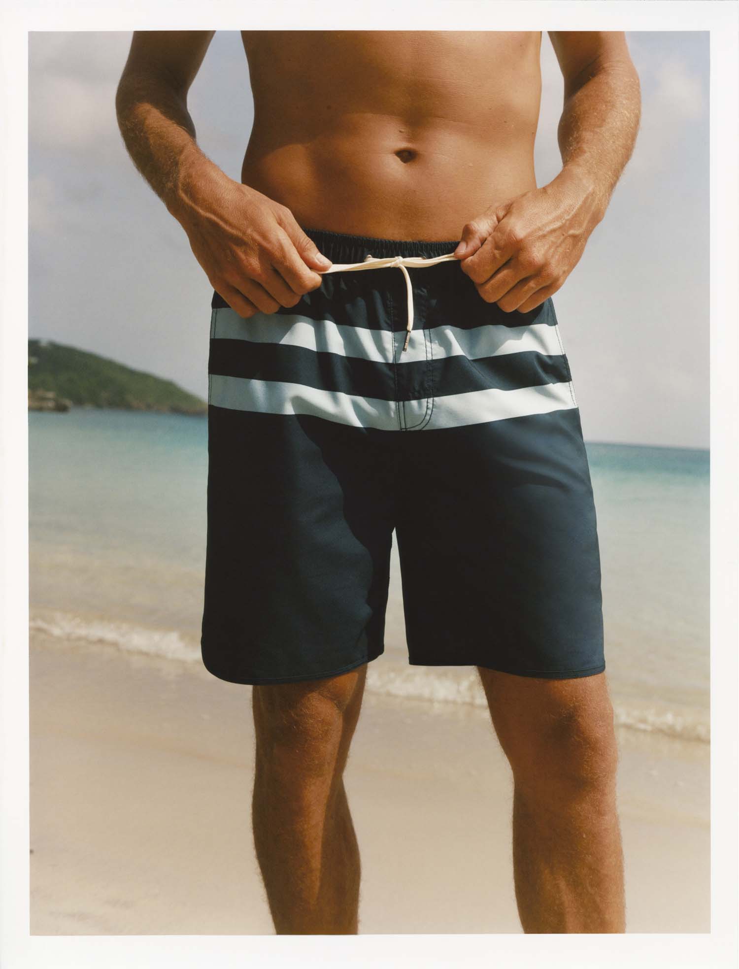Person wearing Anchor Trunk in striped navy color swim shorts on a beach