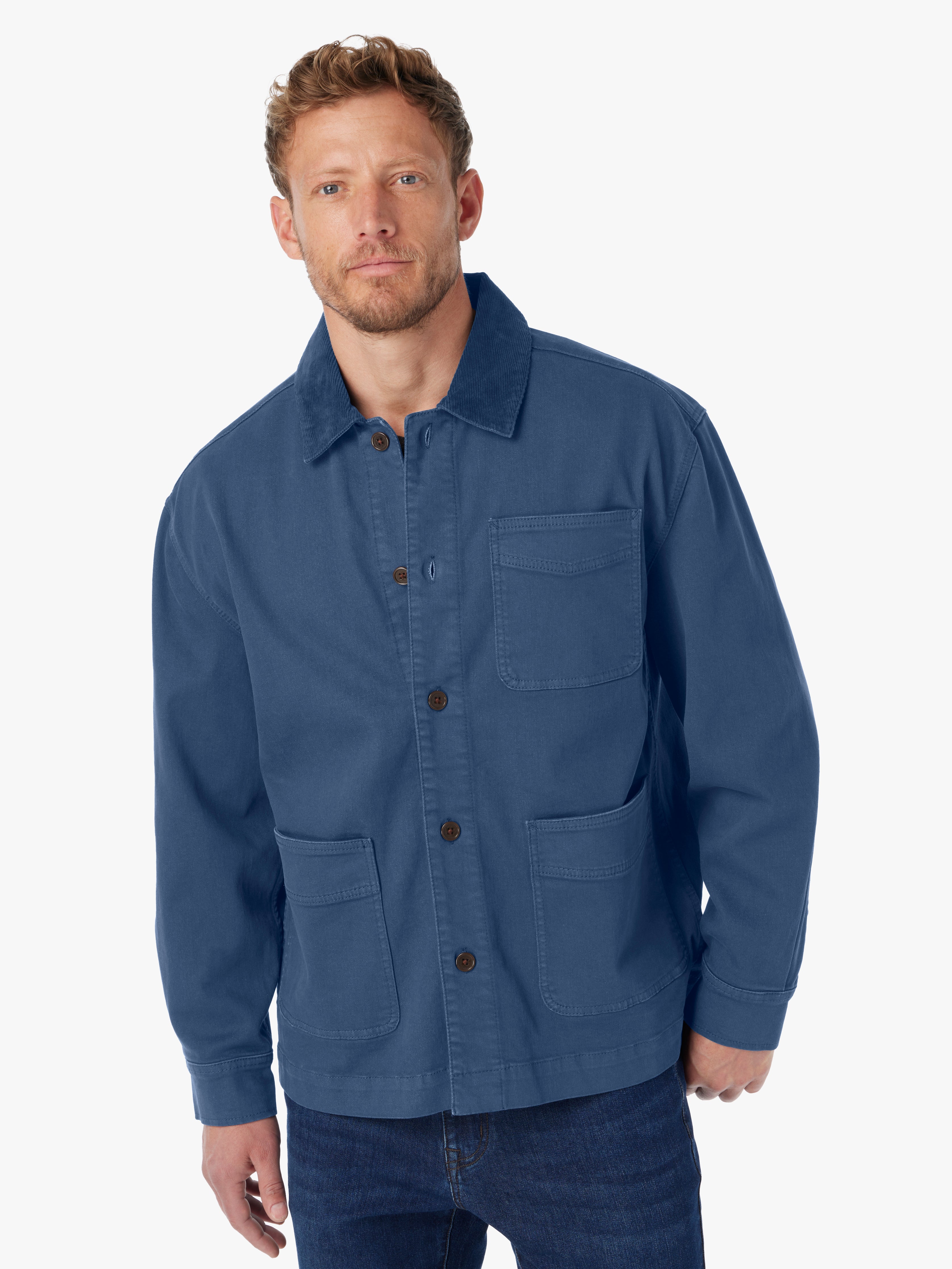 Man wearing blue barn style jacket with brown button details and tonal corduroy collar on a white background