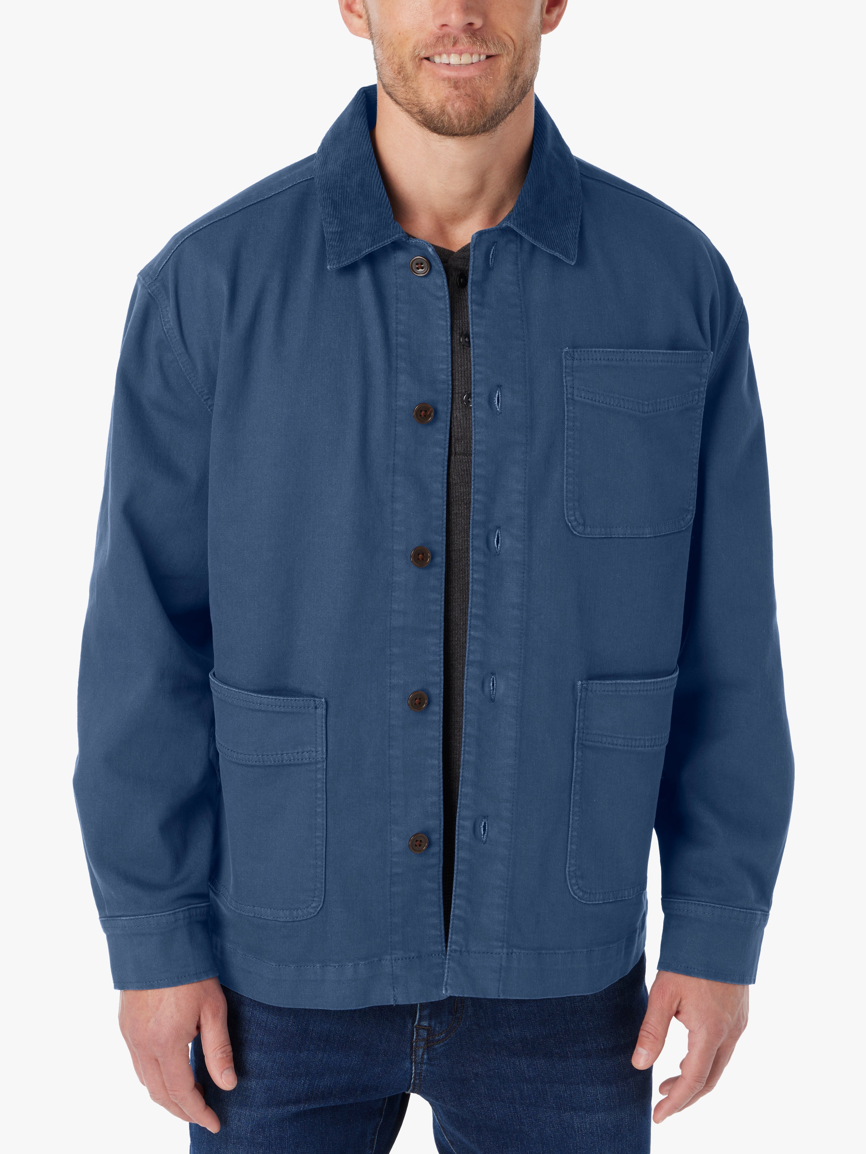 Man wearing blue barn style jacket with brown button details and tonal corduroy collar on a white background. 