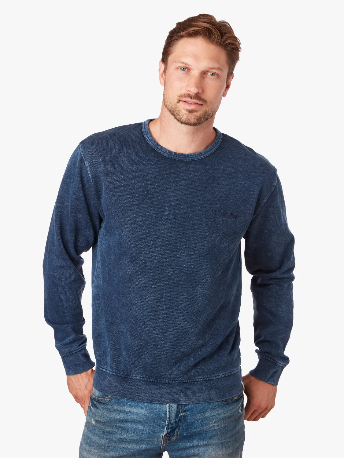 Man wearing a navy blue saltaire sweatshirt and jeans on a white background