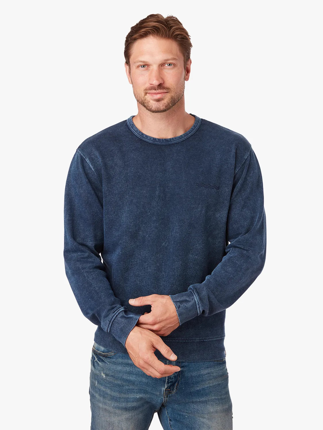 Man wearing a navy blue saltaire sweatshirt and jeans on a white background
