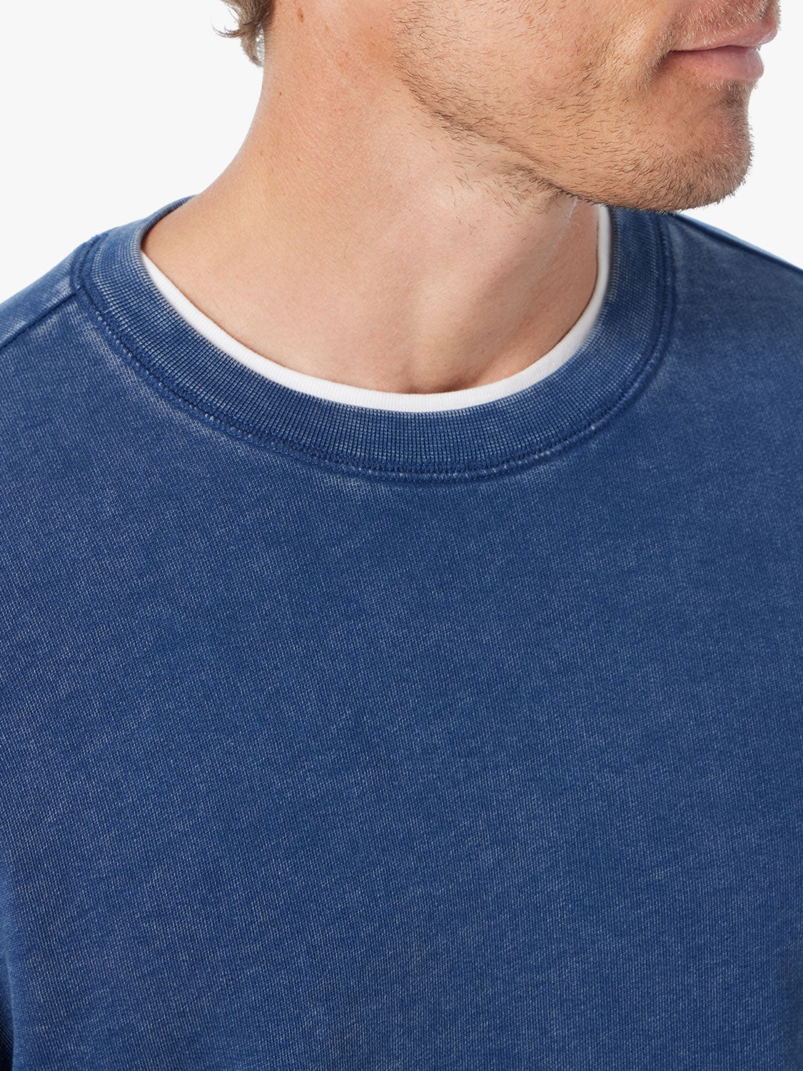 Close-up of person wearing navy blue saltaire sweatshirt on a white background, focusing on neckline. 