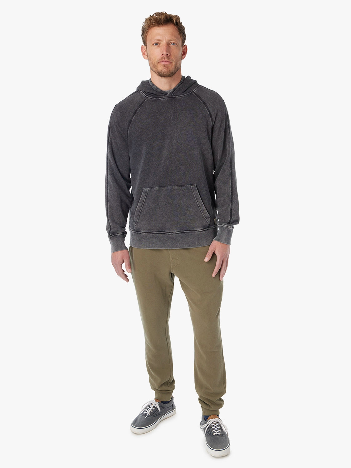 Man wearing a black saltaire hoodie and olive green pants on a white background