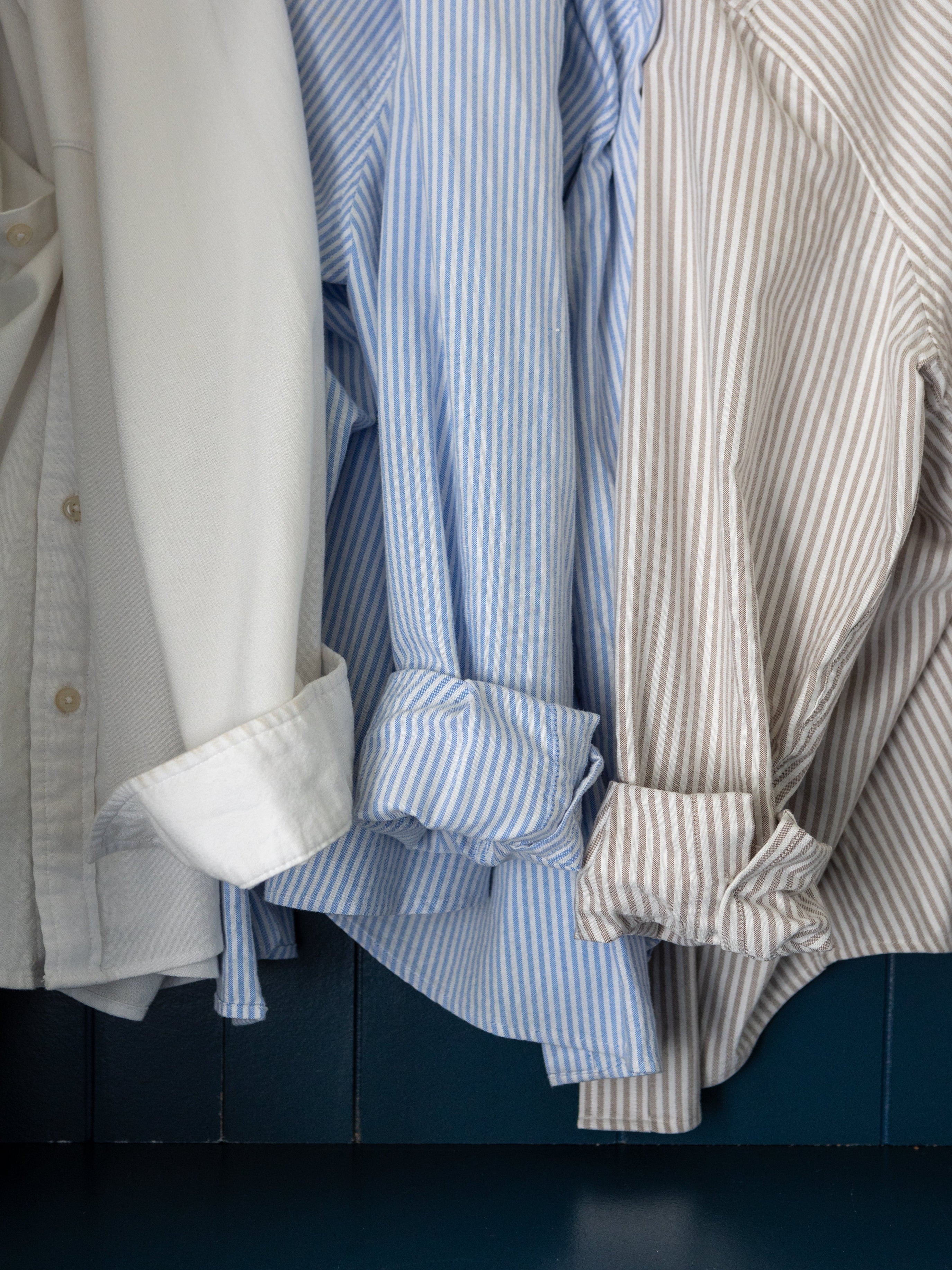 Stack of folded shirts in various colors against a dark background