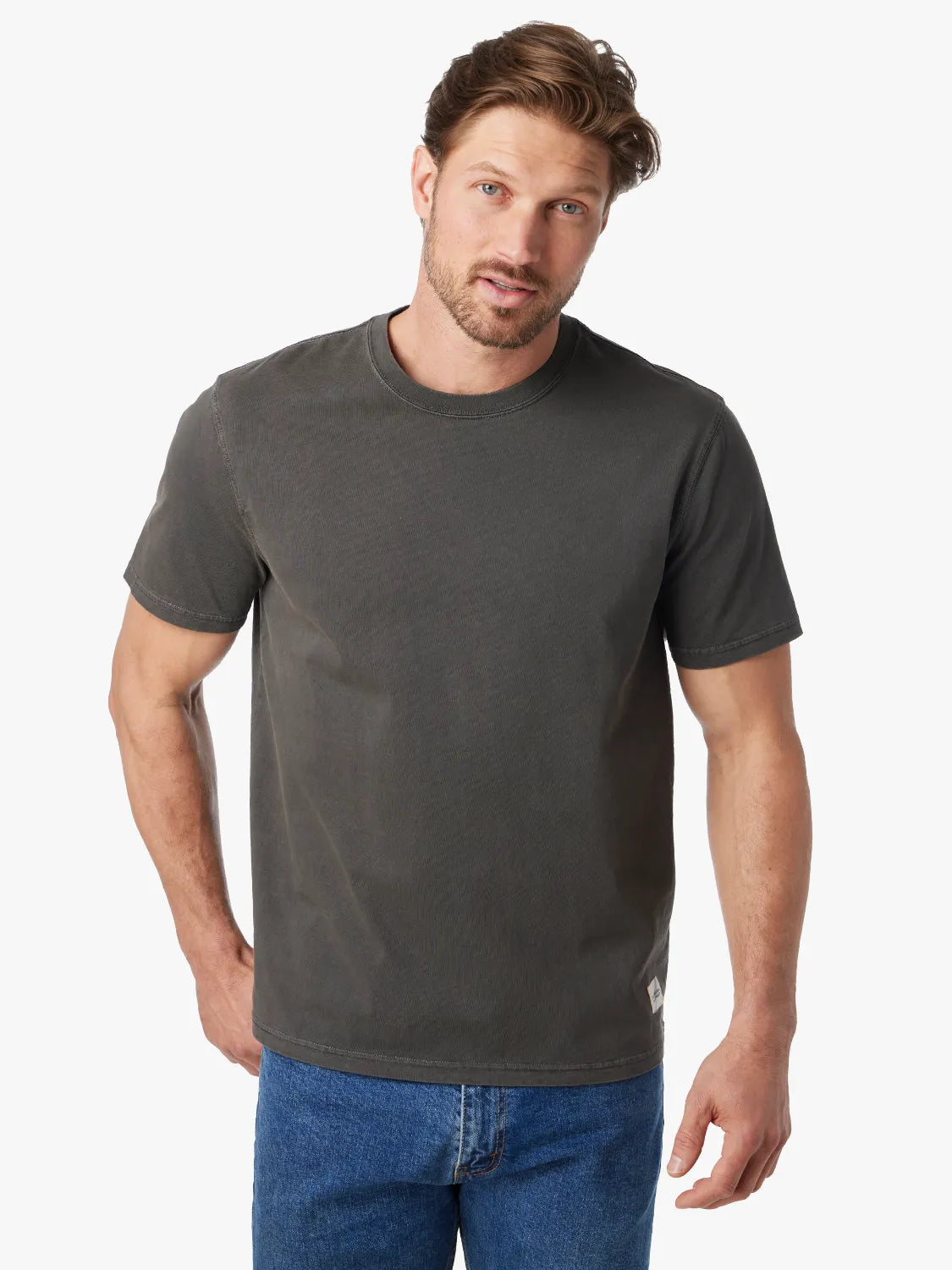 Person wearing black saltaire t-shirt on a white background, paired with denim pants.