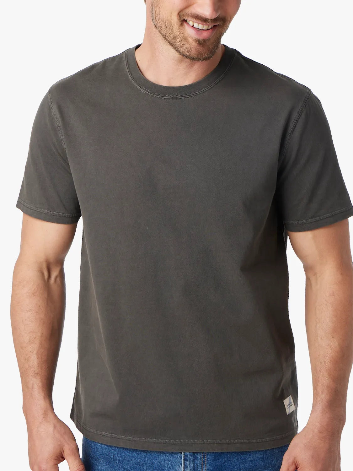 Person wearing black saltaire t-shirt on a white background, paired with denim pants.