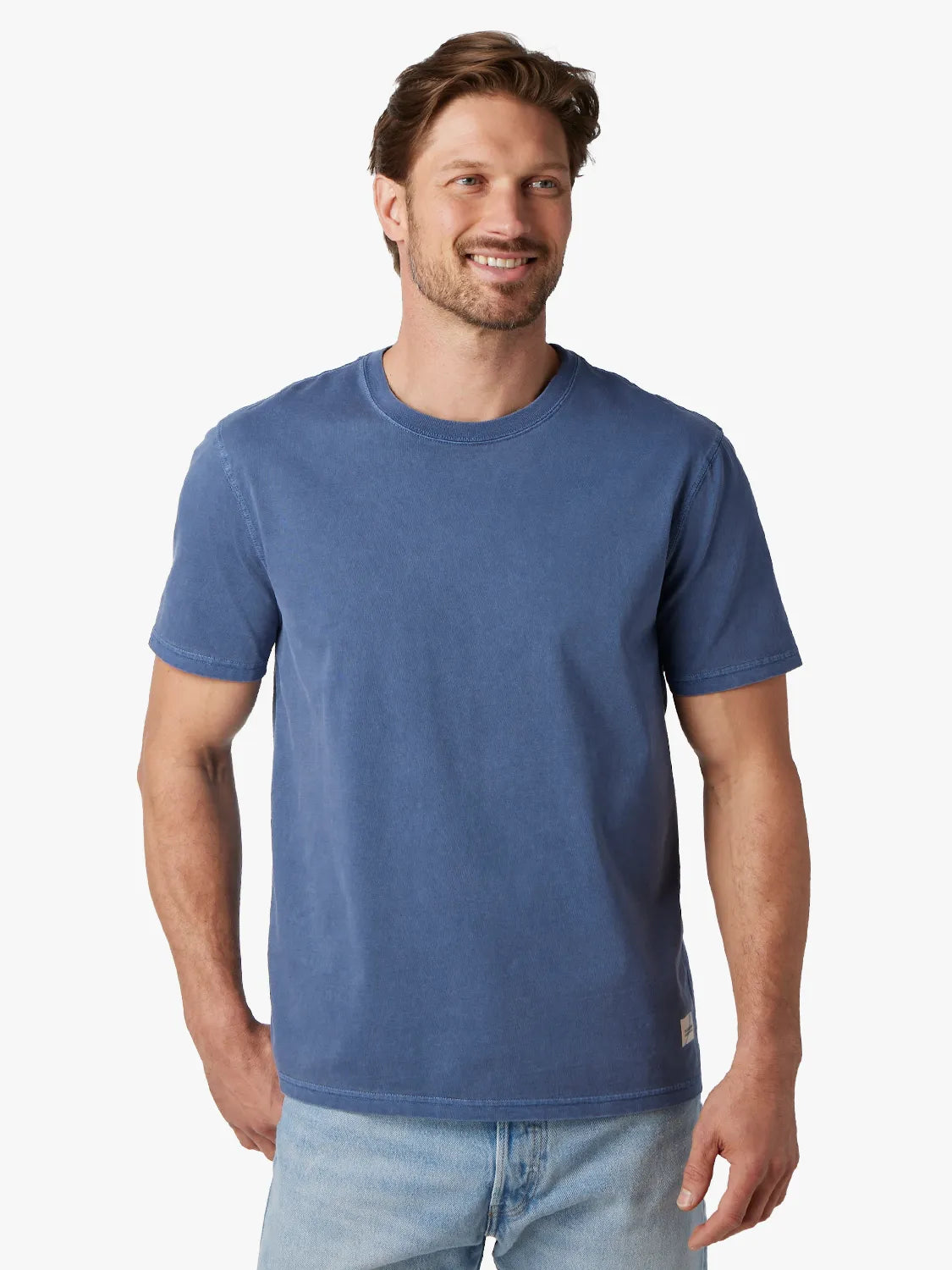 Person wearing navy blue saltaire t-shirt on a white background, paired with driftwood denim pants. 