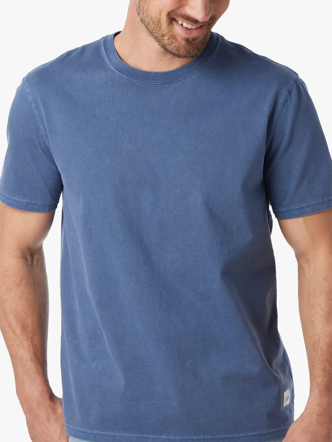 Close up of person wearing navy blue saltaire t-shirt on a white background. 