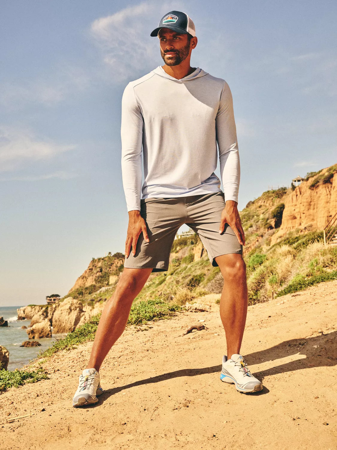 Man wearing slate grey Anchor Trunk and seabreeze hoodie on a hiking trail near the ocean.