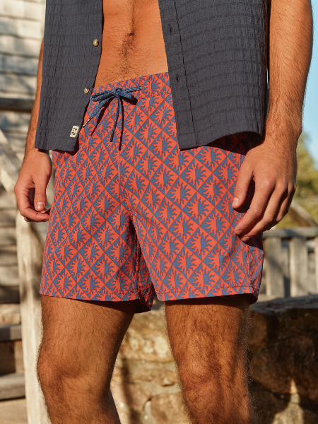 Person wearing red and blue patterned shorts with a vest over shoulders.
