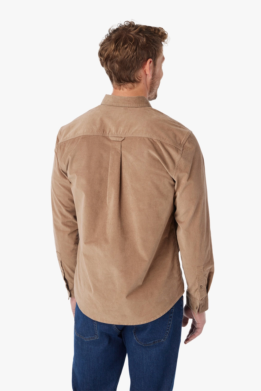 Man wearing a brown corduroy button-up shirt with a white background and  pair of driftwood denim. Showing the back view of shirt. 