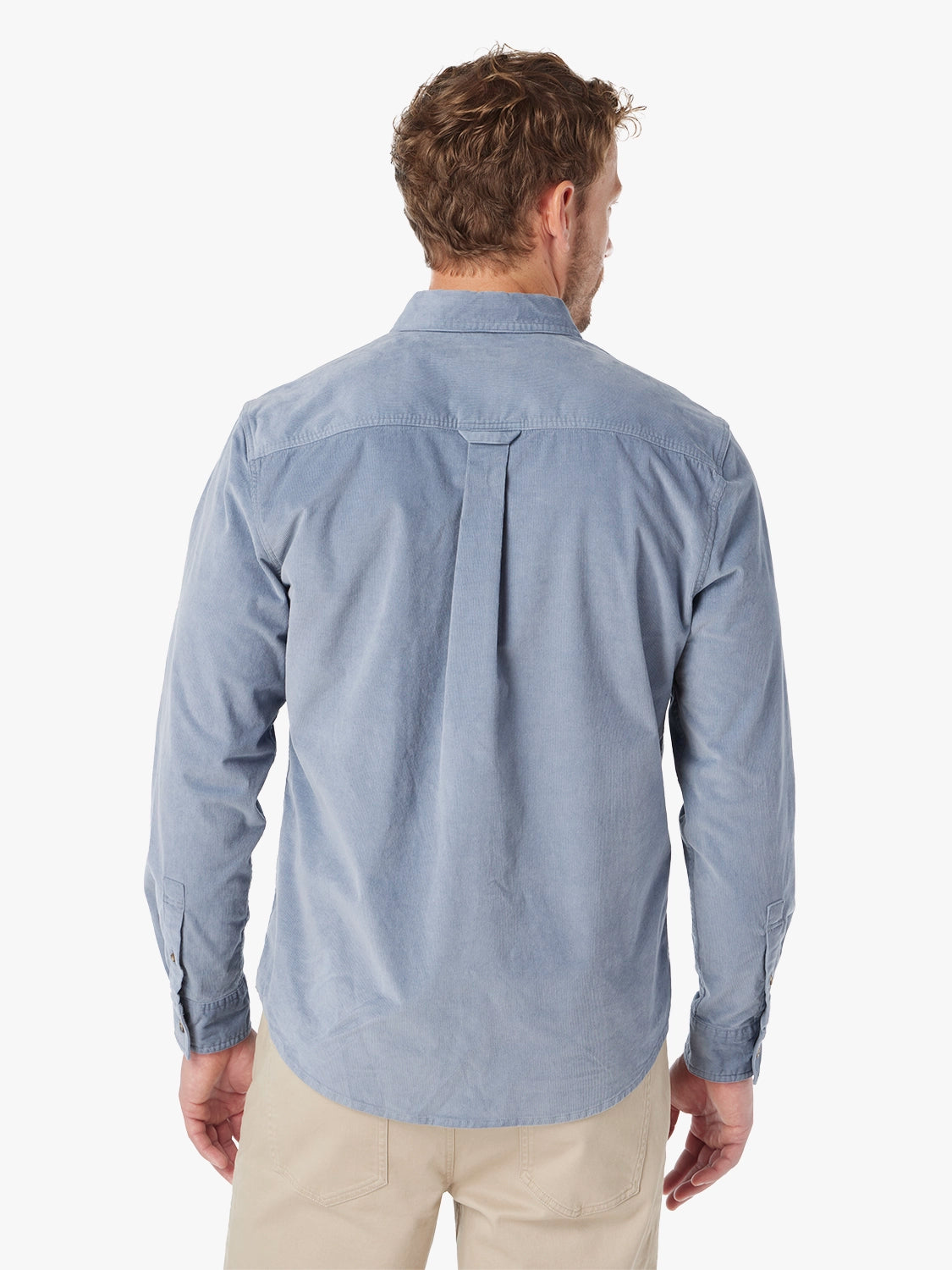 Man wearing blue corduroy button-up shirt on a white background. Paired with khaki horizon pants, showing the back view of shirt.  