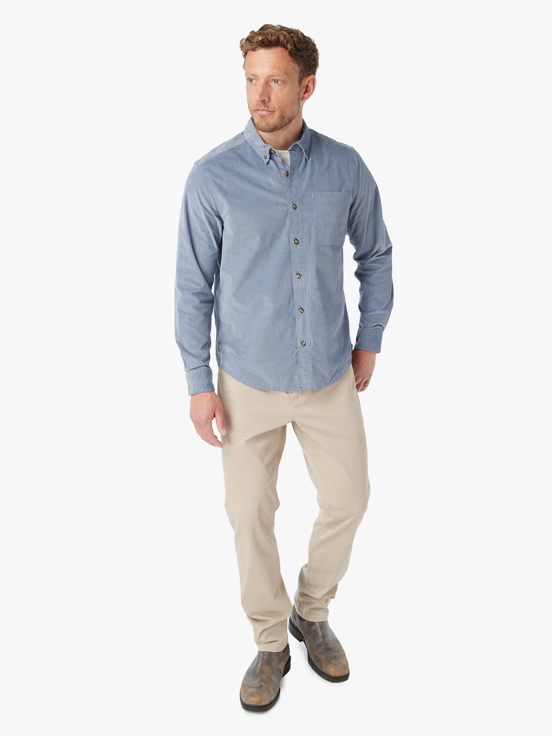 Man wearing blue corduroy button-up shirt on a white background. Paired with khaki horizon pants. 